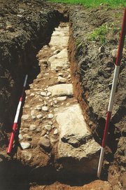 A drainage trench in which the foundation of the gatehouse (large stones) and part of the Kingsbridge Road (small stones) were found.